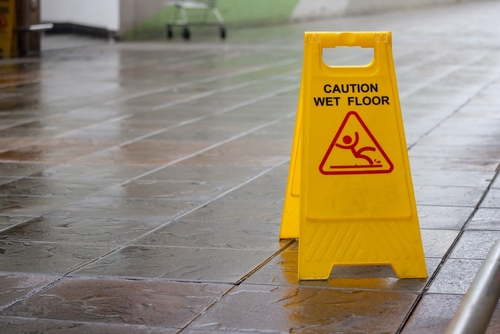 Yellow caution wet floor sign on a wet tile surface.